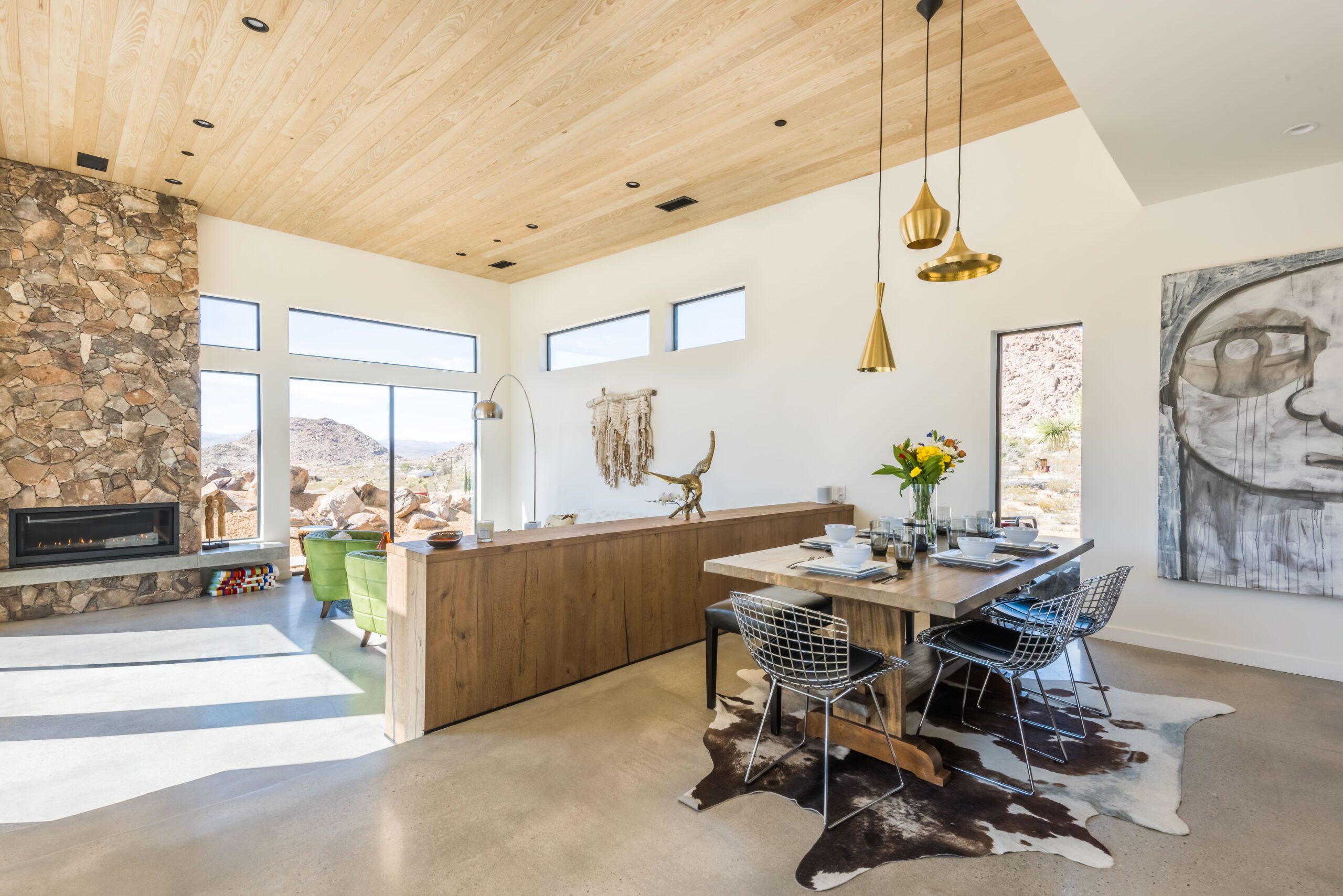 Bright and modern dining room with natural stone accent wall, wood ceiling, and contemporary decor.